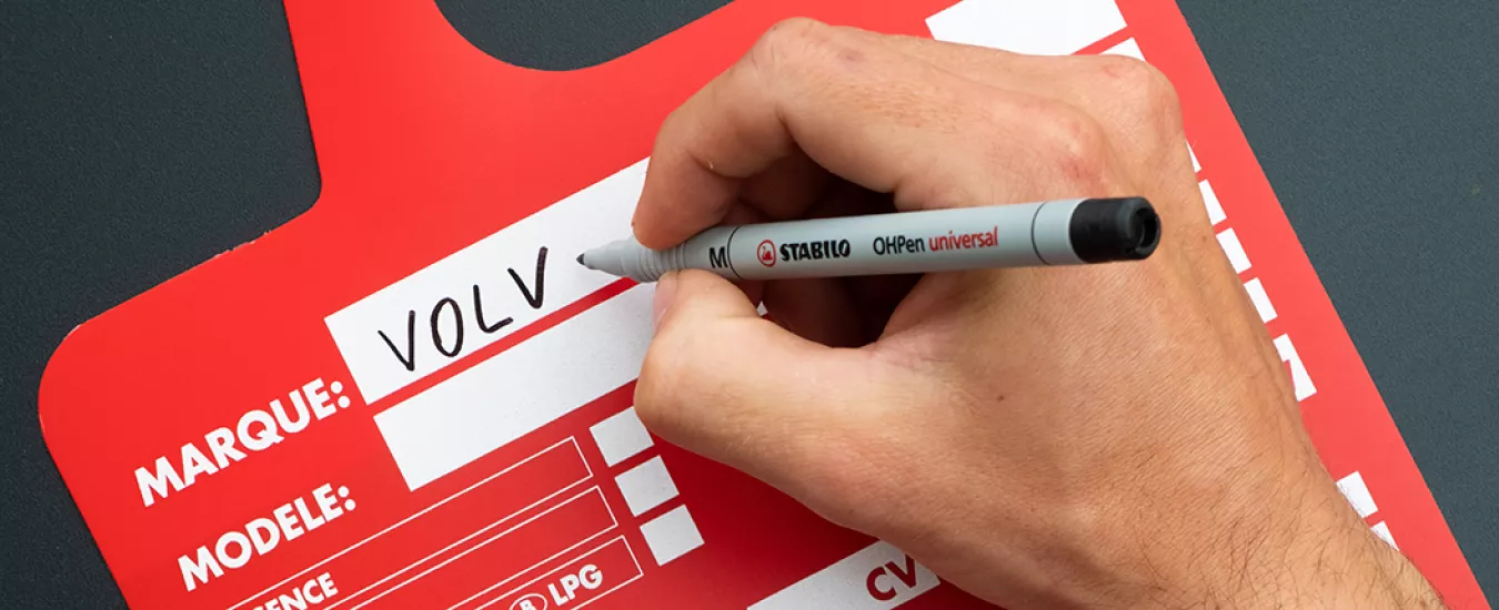 Person writing with a black Marker on a red Sales Card