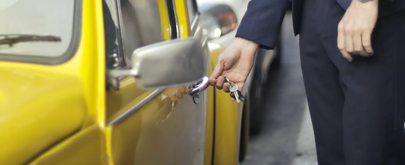 Persona abriendo un auto amarillo con las llaves de su auto