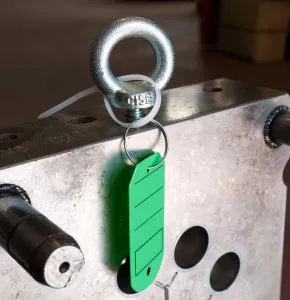 Weiße Kabelbinder an grünem Schlüsselanhänger und Maschine befestigt