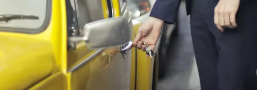 Persoon opent een gele auto met zijn autosleutels